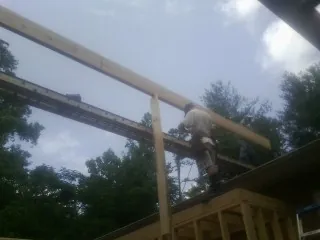 Carpenter setting a ridge beam over a new addition frame — Ice Dam Removal by Roofing Brothers in Howe