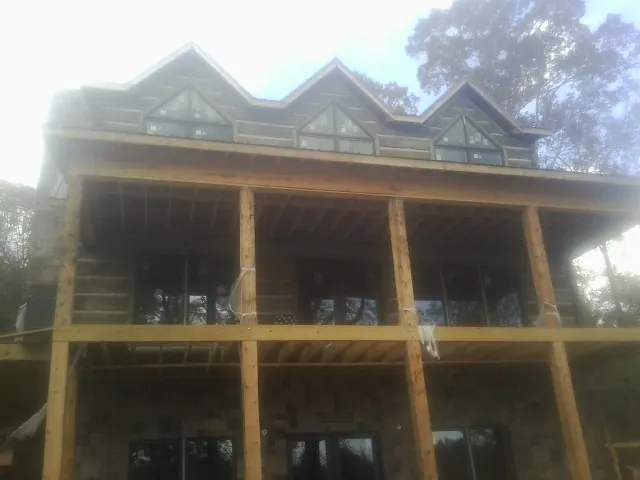 Dormers and porch framing on a large log home under construction — Roof Coating work by our crew in Howe
