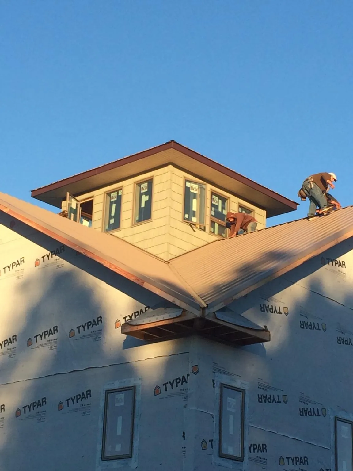 Roofers working around a rooftop cupola on a new metal roof at sunset — Roof Waterproofing in Howe by Roofing Brothers